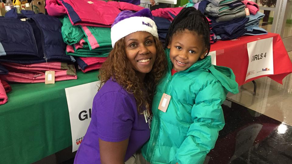 FedEx volunteer talking to child at Operation Warm event