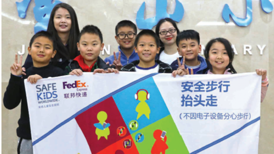 Children in Asia holding a Safe Kids banner