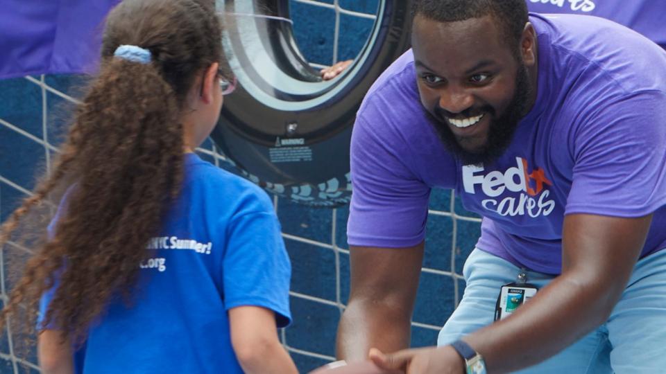 FedEx volunteer playing catch with a child
