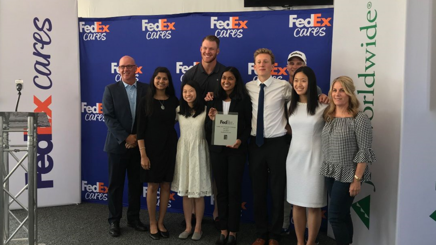 Junior Achievement winners standing in front of a FedEx Cares banner